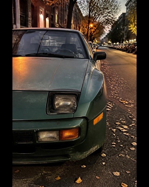 An old green sports car parked on an autumn street