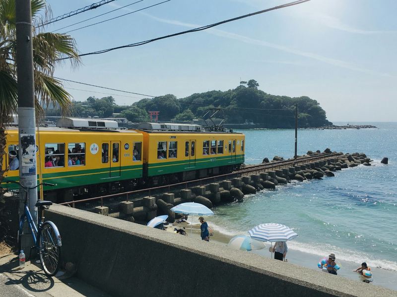 A yellow and green train running along the sea